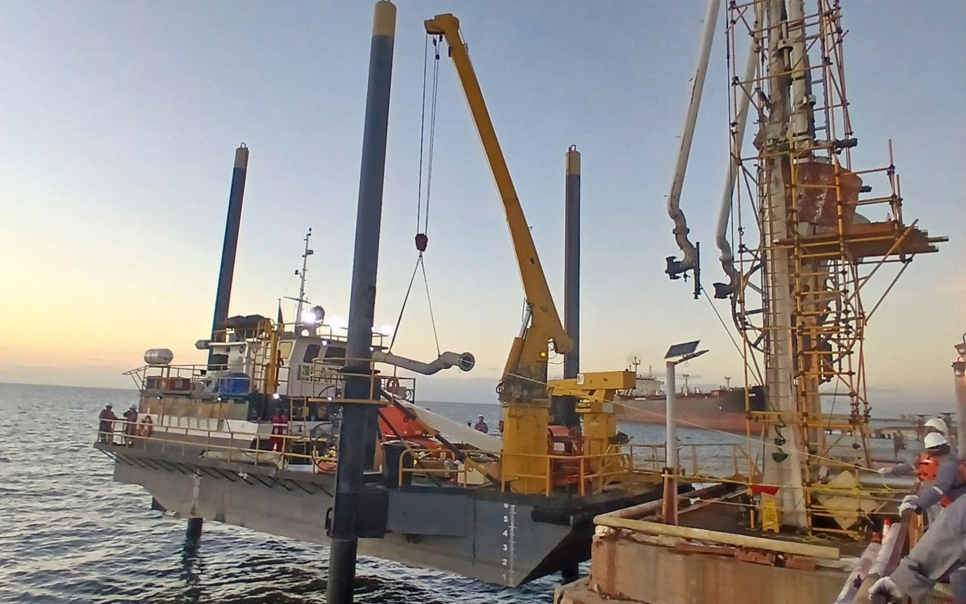 LATICON unit working offshore on Lake Maracaibo, legs lowered to the bottom and deck crane deployed alongside a wellhead structure at dusk